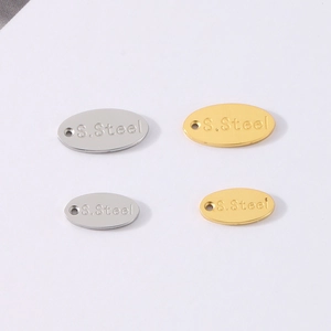 Macro view of gold and silver stainless steel oval charms with S.Steel engraving
