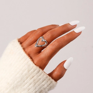 Detail of silver hollow heart ring with hammer texture on female hand with cozy knitwear