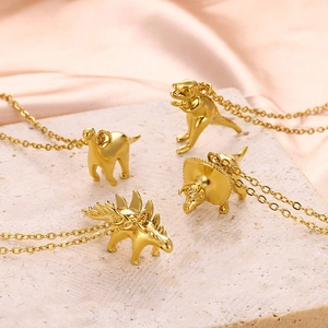 Detail view of four 18K gold plated dinosaur pendant necklaces on silk background
