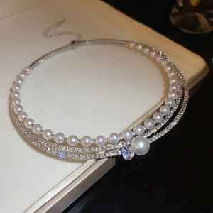 Detail of elegant multi-layer pearl choker with sparkling rhinestones and silver pendant