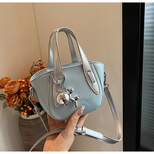 Détail d'un sac à main bleu clair avec poignées argentées et pendentif chien ballon