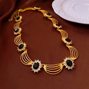 Macro shot of vintage gold chain with black oval gems and sparkling crystal details