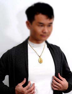 Detail of a men's 18K gold stainless steel religious oval pendant necklace on a male model