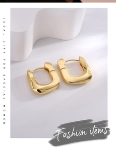 Detailed view of gold-plated geometric U-shaped hoop earrings on elegant white podiums