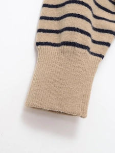 Close-up of ribbed cuffs on a striped knit sweater with soft beige and navy texture