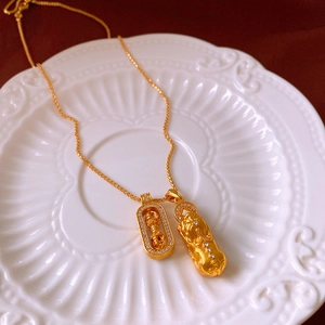 Close-up of golden necklace with zircon-encrusted double pendants on a ceramic plate
