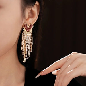 Close-up of heart-shaped red rhinestone earrings with elegant gold chain tassels