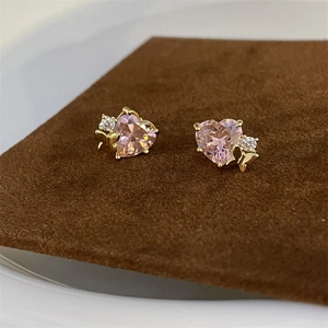 Macro shot of vintage style pink heart zircon earrings on a brown velvet pad