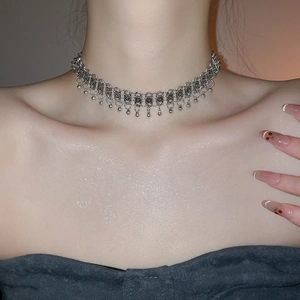Detail of silver vintage metal choker with engraved rings and small beaded tassels
