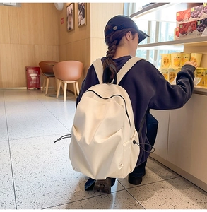 Minimalist beige backpack with side drawstring detail worn in a convenience store