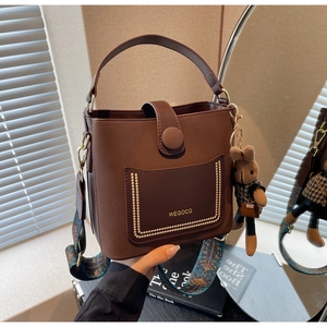 Detail of dark brown leather bucket bag with wide ethnic strap and rabbit charm