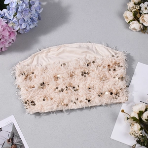 Vista piatta dettagliata del top a fascia color champagne con paillettes e piume chic