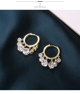 Detail showing gold hoop earrings with sparkling round crystals and fringe drop pendants