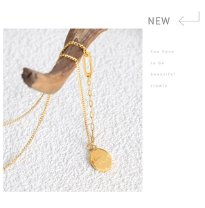 Detail of gold titanium necklace featuring a Good Luck engraved oval pendant on a branch