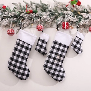 Set of four black and white buffalo plaid Christmas stockings on festive tree branches