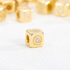 Macro shot of 18K gold plated cube bead with zircon @ symbol for DIY jewelry
