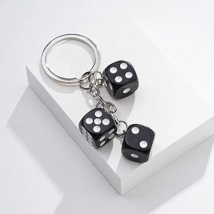 Detail of three black plastic dice keychain pendants with a polished silver metal ring