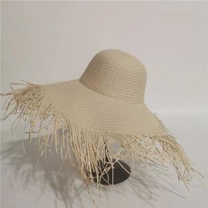 Macro detail of beige woven straw hat featuring wide brim with frayed fringe edges