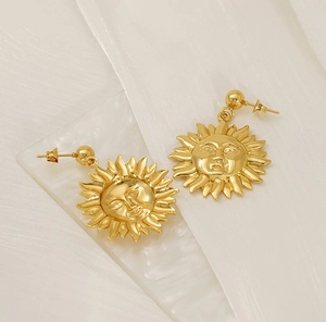 Detailed close-up of gold sun face earrings featuring 18K gold-plated textured rays
