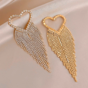 Close-up of heart tassel earrings in silver and gold finish on champagne silk fabric