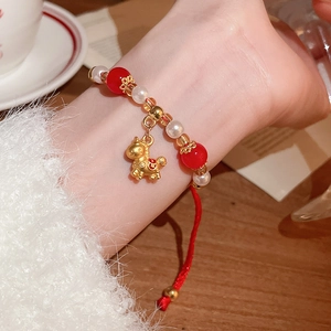 Vue détaillée du bracelet en corde rouge tressée avec pendentif cheval doré et perles