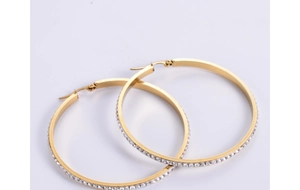 Detailed close-up of large golden hoop earrings featuring a full row of white rhinestones