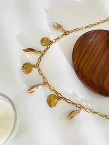 Gros plan d'un collier doré en acier inoxydable avec pendentifs coquillages