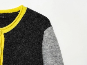 Close-up of color-block knit sweater neckline with yellow ribbing and soft wool texture