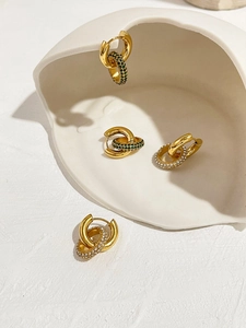 Détail de boucles d'oreilles en or 18 carats avec zircons verts et blancs