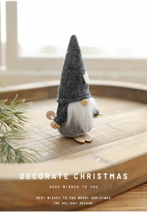 Detail of grey felt Christmas gnome on wooden tray with festive pine branch decor
