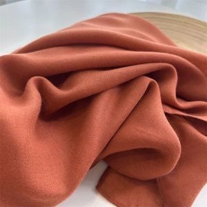 Detailed close-up of burnt orange cotton linen fabric texture with soft natural pleats