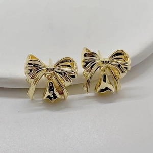 Boucles d'oreilles nœud plaquées or 14K avec clochettes sur un plateau en céramique