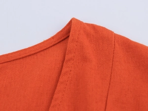 Macro view of V-neck collar detail and orange linen fabric texture with neat stitching