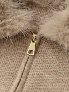 Detail of khaki knit fabric with gold zipper and faux fur collar texture