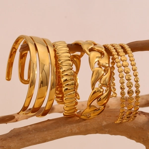 Set of four 18K gold plated stainless steel bangles hanging on a wooden stand