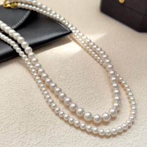 Detailed comparison of two high-gloss pearl necklaces in medium and large bead sizes