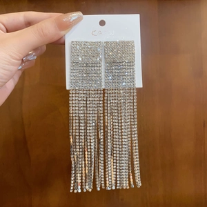 Macro shot of silver tassel earrings with sparkling crystals on a wooden surface
