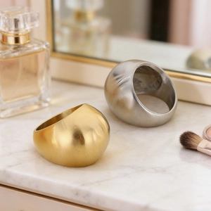 Chunky gold and silver polished metal rings on elegant marble surface display