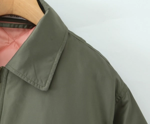 Detail of army green jacket with pink quilted lining and classic turn-down collar