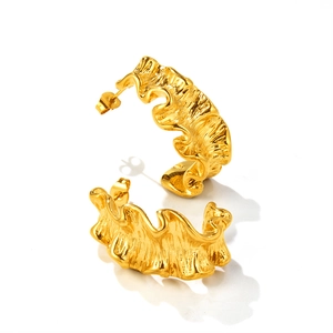 Détail macro de boucles d'oreilles en C dorées avec texture ondulée en acier doré 18k