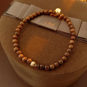 Detail of dark brown agarwood beaded bracelet on a premium velvet gift box with gold bead