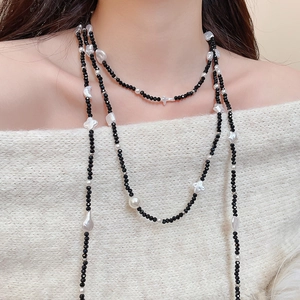 Close-up of beaded necklace with black crystals, pearls, stars and moon charms on a model