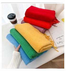 Detailed macro shot showing the soft texture of colorful solid wool scarves with fringes.