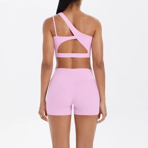 Detail of pink one-shoulder yoga set showing open back sports bra and high waist shorts