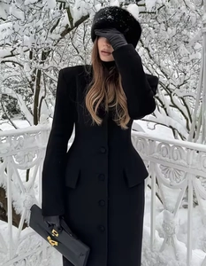 Detail of elegant black wool coat with gold buckle leather clutch and matching winter gloves