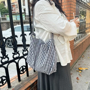 Outdoor shot of a black and white gingham tote bag worn by a model on her shoulder