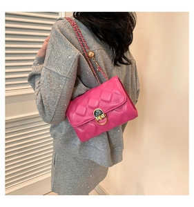 Close-up of pink quilted crossbody bag with gold chain strap worn by a model