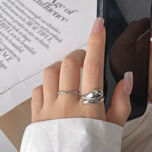 Detail of silver double-layer minimalist rings with irregular drop shape and rope texture