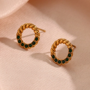 Detailed close-up of golden twisted hoop earrings featuring five round green zircon stones