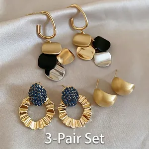 Detail view of a 3-pair earring set featuring gold hoops, blue rhinestones, and satin finish